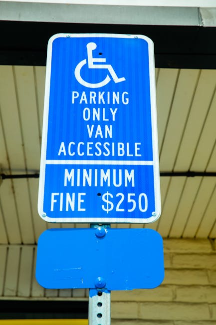 A close-up view of a reserved parking sign indicating van accessibility, mounted on a metal pole with a white background and green lettering that reads 'RESERVED PARKING' along with a wheelchair symbo
